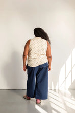 Load image into Gallery viewer, Person wearing a sleeveless patterned top and blue pants standing in a well-lit room.
