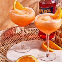 Load image into Gallery viewer, Two orange cocktails with Aperol bottle and orange slices on a woven tray.
