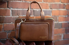 Load image into Gallery viewer, Brown leather bag with a smaller attached pouch against a brick wall.