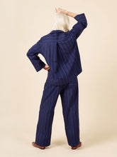 Load image into Gallery viewer, Person wearing a navy pinstripe pajama set on a beige background