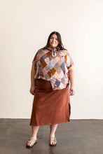 Load image into Gallery viewer, Woman wearing a patterned top and brown skirt against a plain background