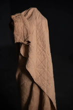 Load image into Gallery viewer, Quilted beige fabric draped over a dark background