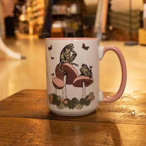 coffee mug with frogs sitting on mushrooms