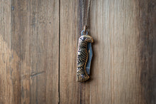 Load image into Gallery viewer, Eagle-shaped pendant on a chain against a wooden background