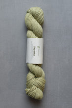 Load image into Gallery viewer, Skein of green yarn with a label on a gray background