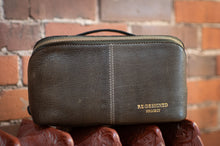 Load image into Gallery viewer, Brown leather pouch with 'RE-DESIGNED PROJECT' text held against a brick wall.