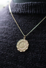 Load image into Gallery viewer, Gold necklace with a round pendant on a black textured sweater