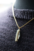 Load image into Gallery viewer, Gold necklace with a shoe-shaped pendant on a dark textured fabric background