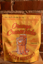 Load image into Gallery viewer, Packaging of Orange Creamsicle frozen cocktails with a drink illustration on a wooden surface.