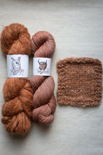 Load image into Gallery viewer, Two skeins of yarn in brown and pink with a knitted swatch on a light gray background.