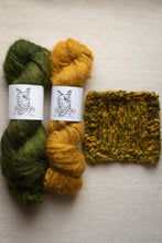 Load image into Gallery viewer, Two skeins of green and yellow yarn with labels, next to a knitted swatch on a beige background.