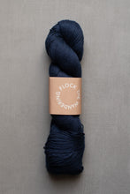 Load image into Gallery viewer, Navy skein of yarn with a label on a gray background