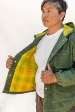 Load image into Gallery viewer, Person wearing a green jacket with a yellow lining against a white background