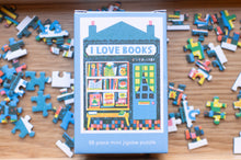 Load image into Gallery viewer, Mini jigsaw puzzle box with 'I Love Books' design on a wooden surface with scattered puzzle pieces.