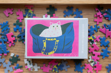 Load image into Gallery viewer, Jigsaw puzzle box with a cat design on top of scattered puzzle pieces