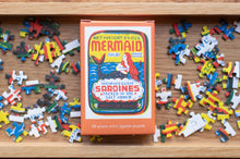 Load image into Gallery viewer, Mermaid-themed mini jigsaw puzzle box with scattered puzzle pieces on a wooden surface