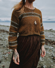 Load image into Gallery viewer, Person wearing a brown knitted sweater with striped patterns on a beach.