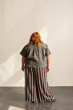 Load image into Gallery viewer, Person wearing a green top and striped pants standing against a plain wall.