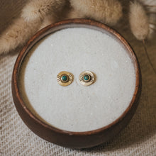 Load image into Gallery viewer, Pair of gold earrings with green gemstones in a wooden bowl.