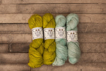 Load image into Gallery viewer, Four skeins of yarn in yellow and green on a wooden surface