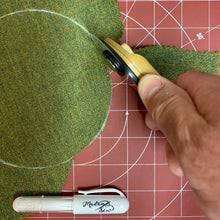 Load image into Gallery viewer, Hand using a rotary cutter on green fabric with a red cutting mat