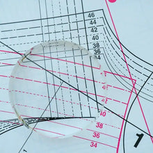 Load image into Gallery viewer, Clear plastic circle with measurement markings on a grid background