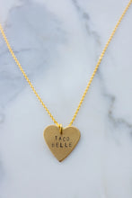 Load image into Gallery viewer, Gold heart-shaped necklace with 'TACO BELLE' engraving on a marble background