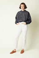 Person wearing a dark gray shirt and white pants on a plain background