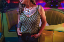 Load image into Gallery viewer, Woman wearing a green knitted tank top with tattoos visible, standing in a colorful indoor setting.
