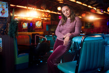 Load image into Gallery viewer, Woman sitting in a dimly lit arcade or game.