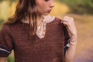 Woman wearing a brown knitted top with lace details outdoors
