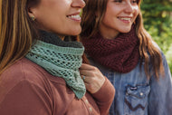 Two women wearing scarves, one green and one maroon, standing close together outdoors.
