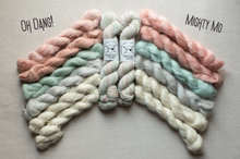 Load image into Gallery viewer, Four skeins of twisted yarn arranged in a fan shape on a light beige fabric background. The yarn colors are dusty pink, mint green, cream, and off-white.