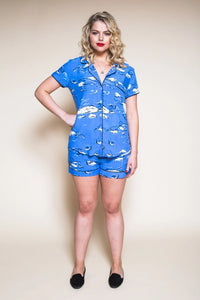 Woman wearing a blue pajama set with cloud pattern on a beige background