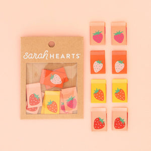 Packaged strawberry-themed items with 'sarah Hearts' branding on a pink background