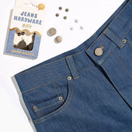 Blue jeans with added buttons and a package of additional buttons on a white background