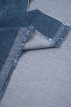 Load image into Gallery viewer, Close-up of blue denim fabric with frayed edges on a matching fabric background