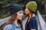 Two women wearing knit hats outdoors with a blurred background