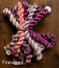 Load image into Gallery viewer, Colorful yarn skeins on a wooden surface with 'Fireweed' branding.