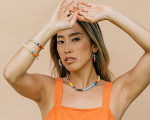 Load image into Gallery viewer, Woman wearing colorful jewelry against a beige background