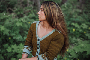 Woman wearing a brown cardigan with floral patterns in a forest setting