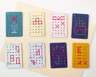 Set of embroidered cards with various designs on a beige background