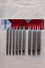Load image into Gallery viewer, Ten metal knitting needles arranged in two rows of five on a light fabric background, with a red and white ChiaoGoo QUADS card placed behind them.