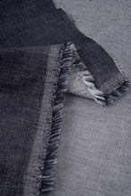 Load image into Gallery viewer, Close-up of dark denim fabric with frayed edges on a gray background