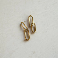 Gold chain-style earrings on a light gray background