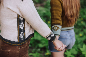 Two people holding hands with focus on their clothing in a natural setting