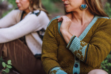 Load image into Gallery viewer, Woman wearing a brown and blue patterned sweater sitting outdoors.