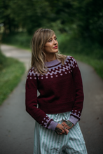 Load image into Gallery viewer, Woman wearing a patterned sweater standing on a path with greenery in the background
