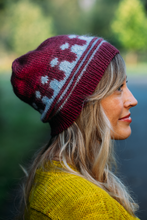 Load image into Gallery viewer, A woman in profile wearing a burgundy and white patterned knit beanie and a yellow knit sweater, set against a blurred outdoor background.