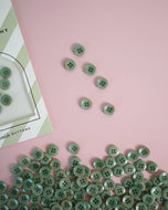 Green buttons scattered on a pink surface with a card labeled 'Buttons' in the corner.